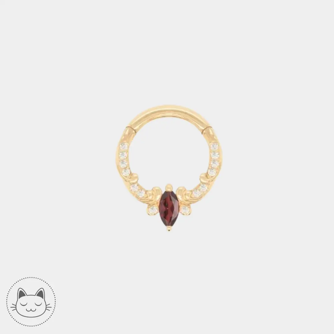 Bijou Buddha Jewelry Coterie en or jaune 14 carats avec grenat rouge et zircons, idéal pour piercing daith ou septum, disponible chez Kawaii Place à Lille.